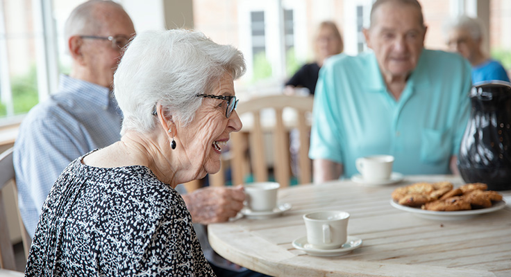 A group of senior citizens chatting over coffee and cookies